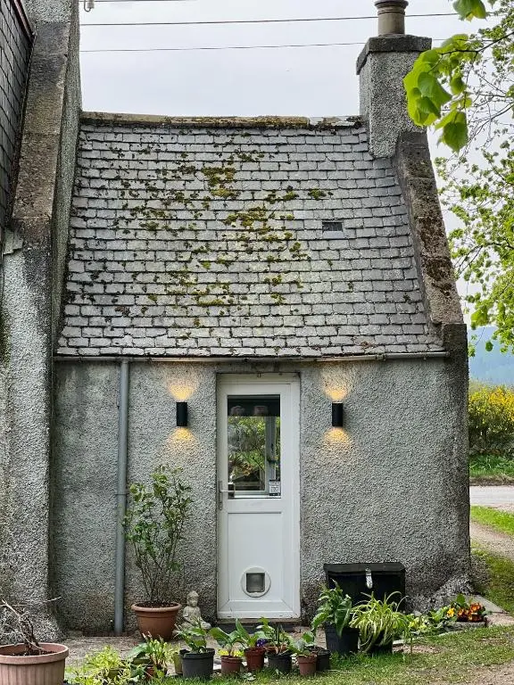 a small stone house with a white door at Cosy Country House in Deeside in Finzean