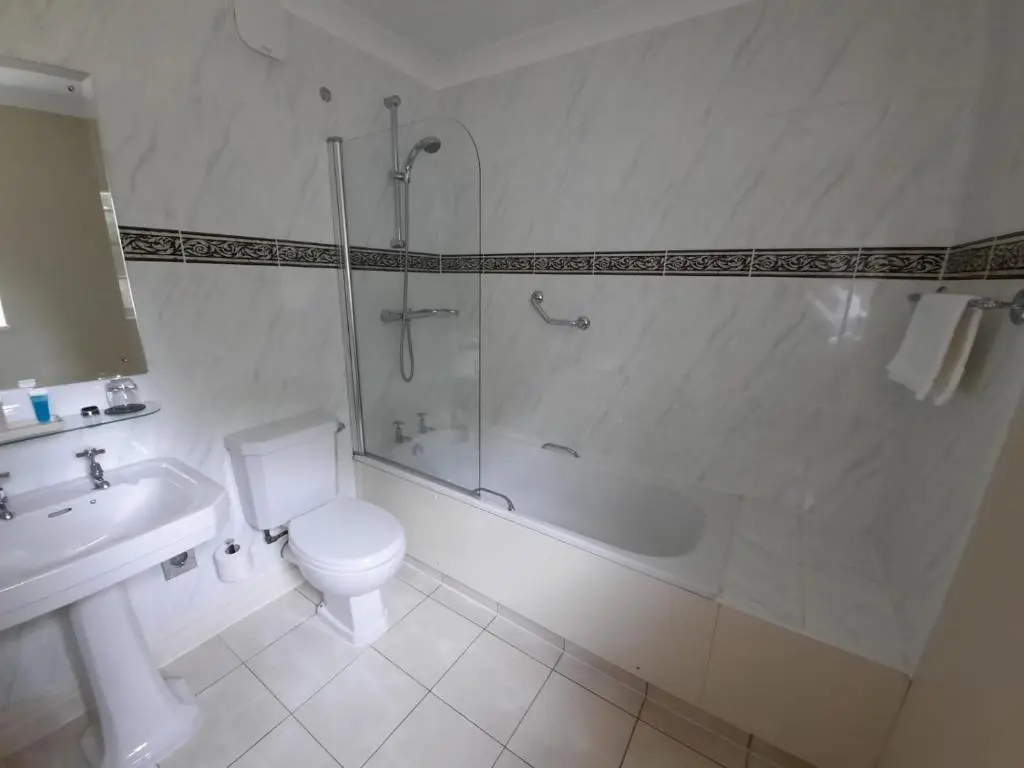 a bathroom with a shower and a toilet and a sink at Macdonald Pittodrie House in Chapel of Garioch