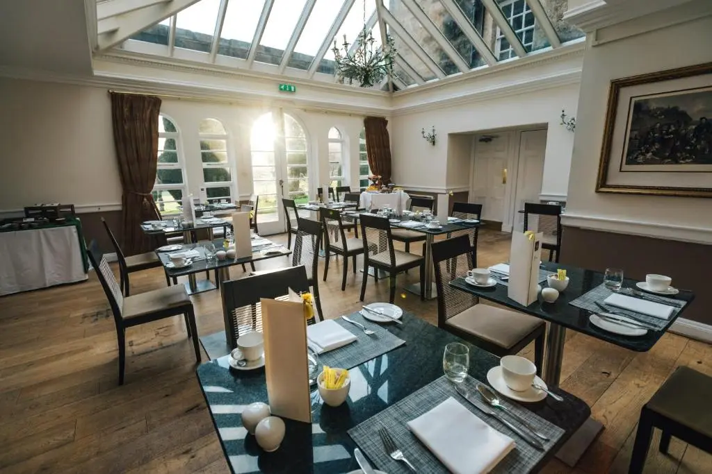a restaurant with tables and chairs and a glass ceiling at Macdonald Pittodrie House in Chapel of Garioch