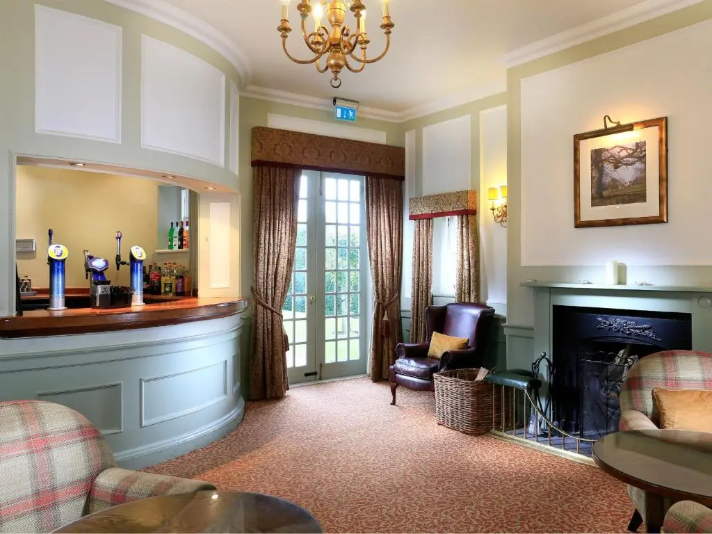 a living room with a fireplace and a chandelier at Macdonald Pittodrie House in Chapel of Garioch