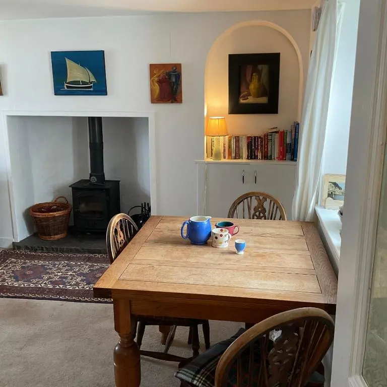 a dining room table with chairs and a stove at A cosy seaside cottage in Cullen