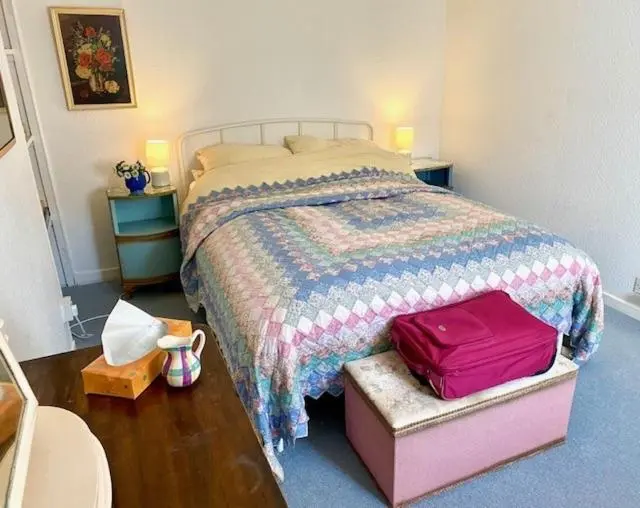 a bedroom with a bed with a pink suitcase at A cosy seaside cottage in Cullen