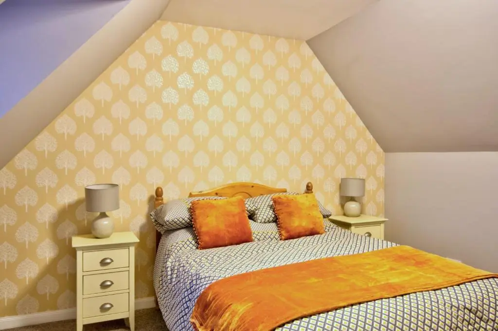 a bedroom with a bed and two night stands at Otago Cottage, Brora in Brora