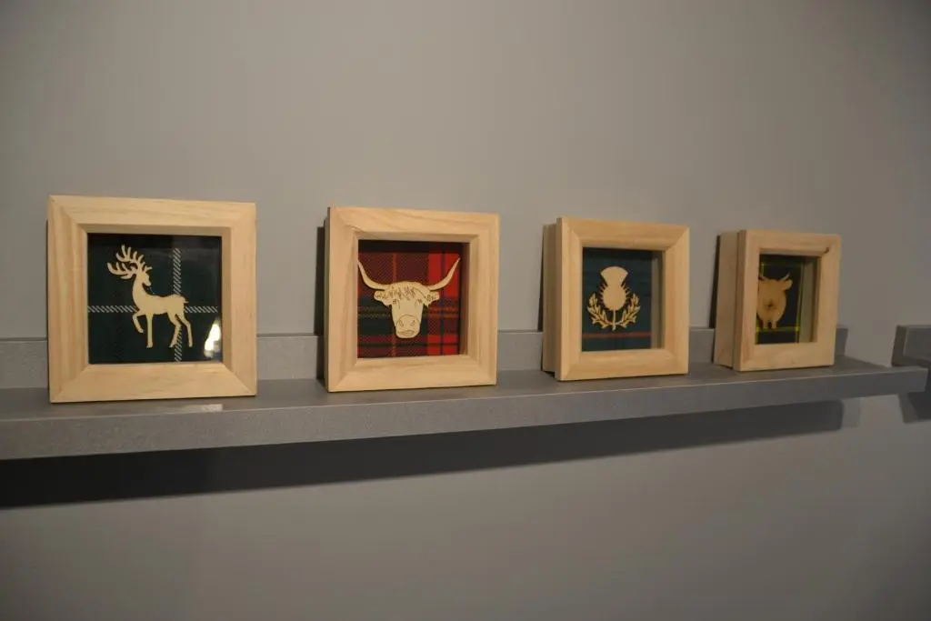 a row of framed photos on a shelf at Otago Cottage, Brora in Brora