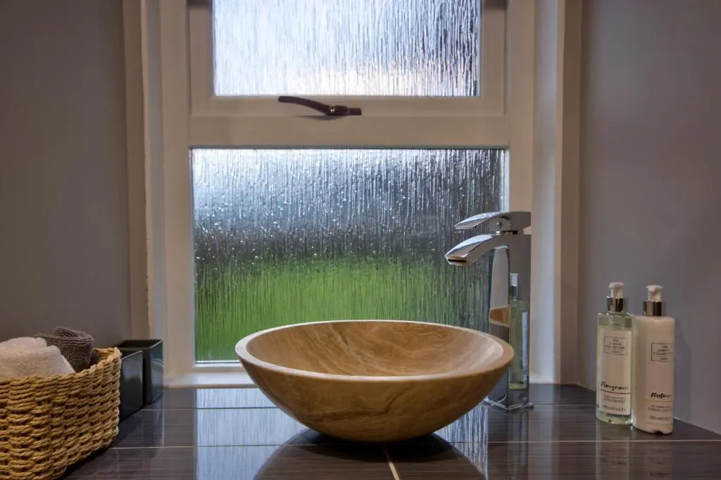 a bathroom with a wooden bowl sink in front of a window at Otago Cottage, Brora in Brora