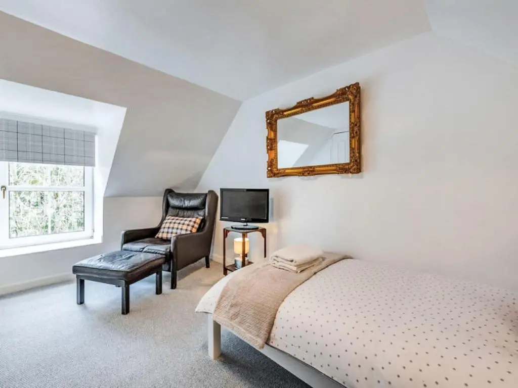 a bedroom with a bed and a chair and a mirror at Holiday Home Dancot by Interhome in Invermoriston