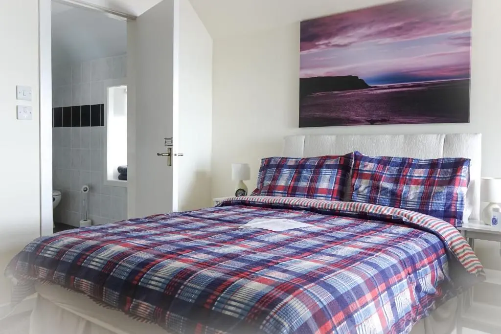 a bed with a plaid comforter in a bedroom at The Pennan Inn in Pennan
