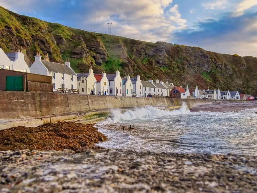 a row of houses on the shore of a beach at The Pennan Inn in Pennan