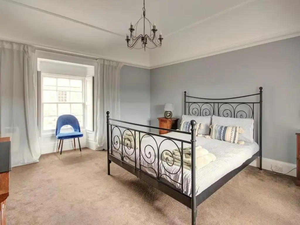 a bedroom with a black bed and a blue chair at Anvil House, Golspie in Golspie