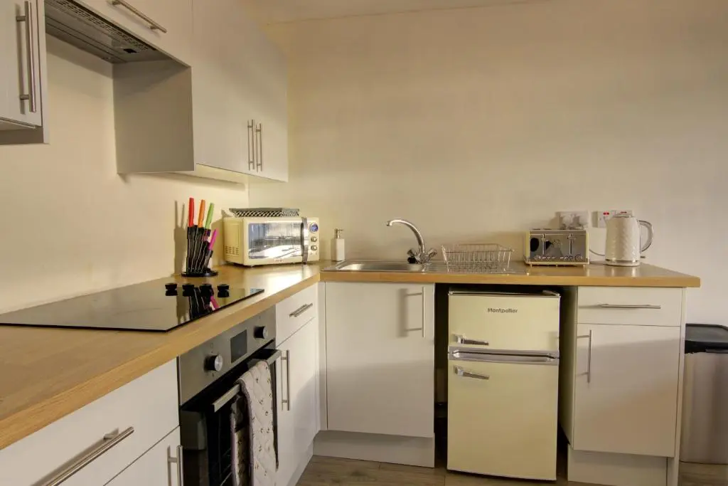 a kitchen with white cabinets and a refrigerator at Tigh-na-Mara, Helmsdale in Helmsdale