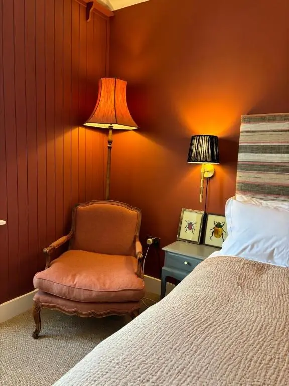 a bedroom with a bed and a chair and a lamp at Hootananny in Inverness