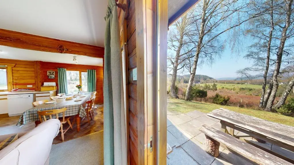 a kitchen and dining room with a table and a bench at Balbeag Cottage in Insh
