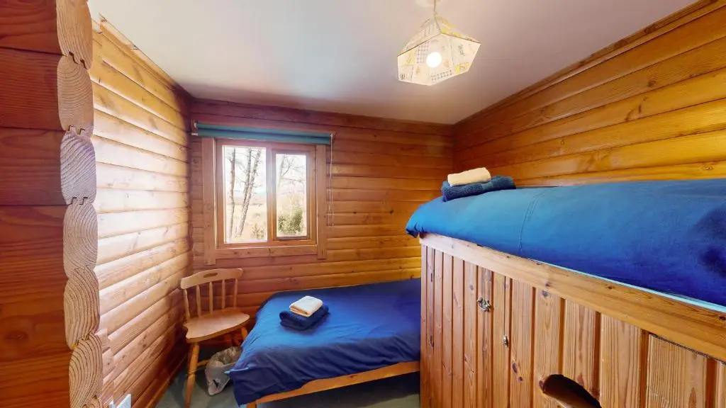a bedroom with two beds in a log cabin at Balbeag Cottage in Insh