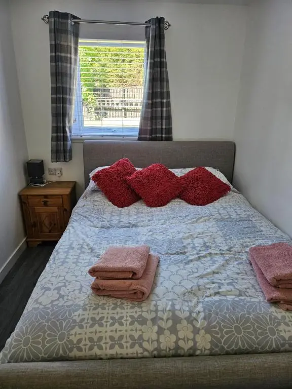 a bedroom with a bed with red pillows and a window at 5 Fulmar Road**Next to West Beach and Golf Course in Lossiemouth