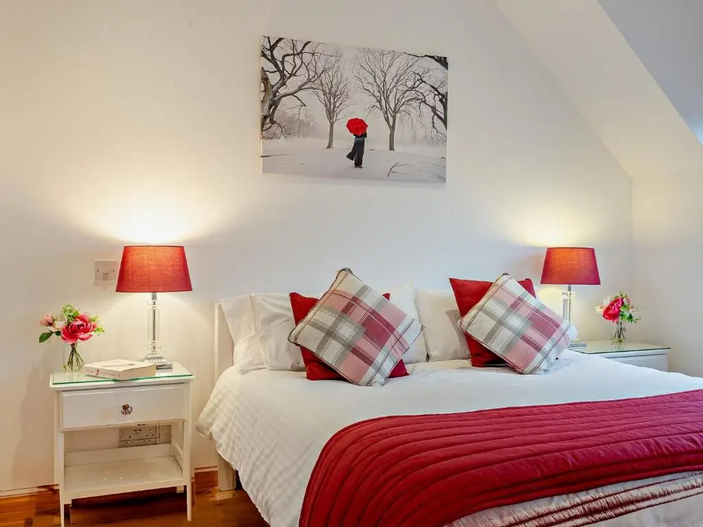 a bedroom with a bed with a red blanket and two lamps at 3 Bed in Grantown-on-Spey 94514 in Grantown on Spey