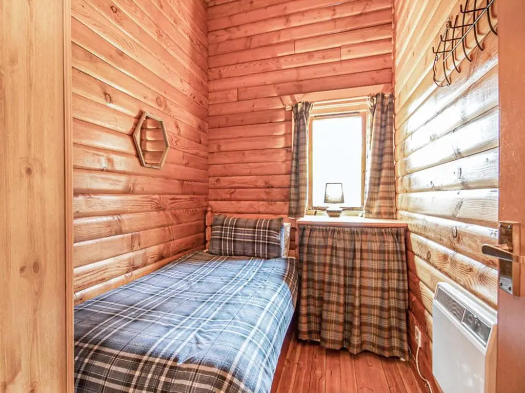a bedroom with a bed in a wooden cabin at Lochside Log Cabin in Brora