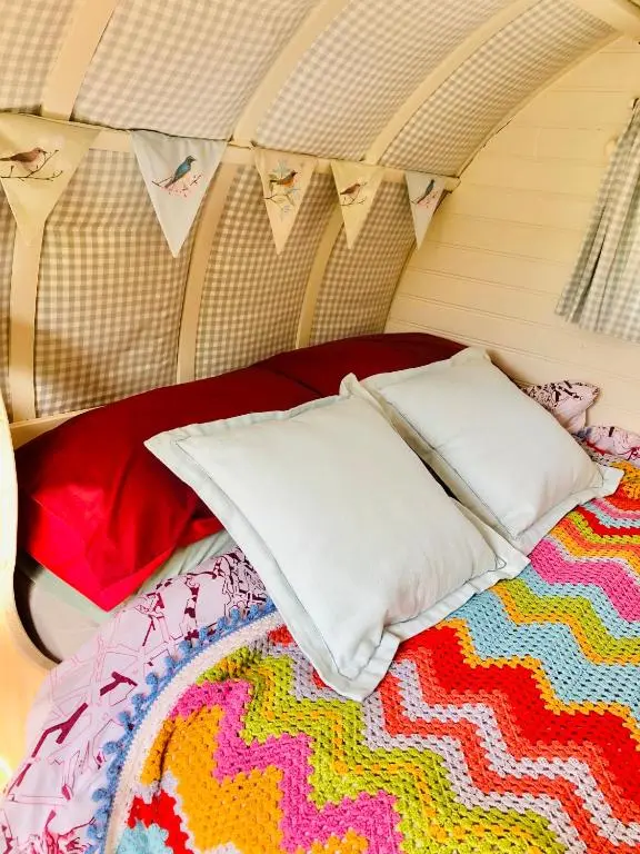 a bed with two pillows and a colorful rug at Bowtop Wagon at Lettoch Farm in Keith