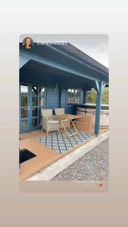 a blue building with a table and chairs on a deck at Retreat Hot Tub Highland Cabin in Inverness