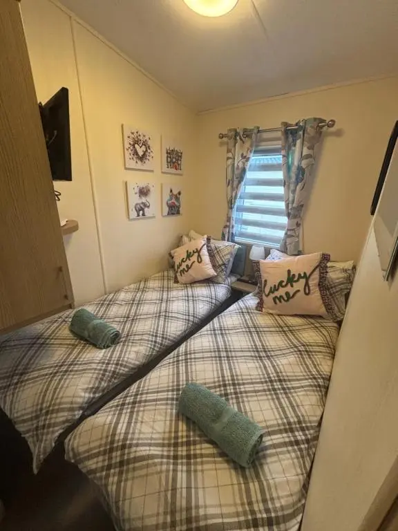 two twin beds in a room with a window at Silversands Holiday Park in Lossiemouth