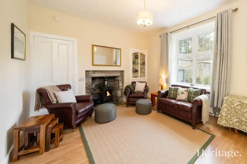 a living room with leather furniture and a fireplace at Station Cottage Dinnet, Aboyne in Aboyne