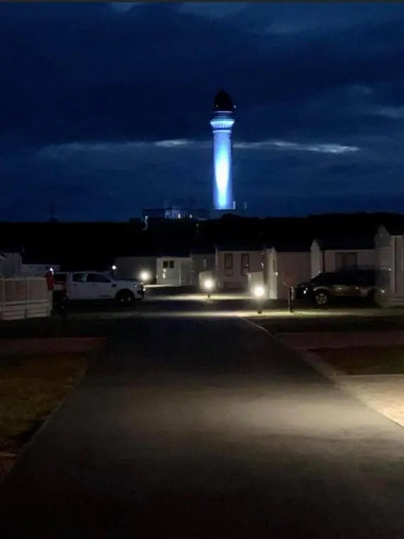 a lighthouse at night with a car parked in a parking lot at Cozy\u2019s caravan hire in Lossiemouth
