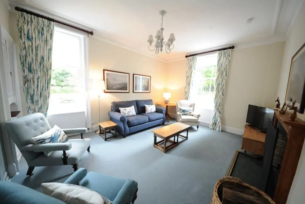 a living room with a blue couch and chairs at Cray House - Large Country Home in Perthshire in Cray