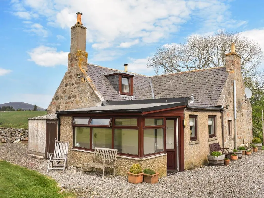 an old stone house with a conservatory with two chairs at Mid Bellandy in Ballindalloch
