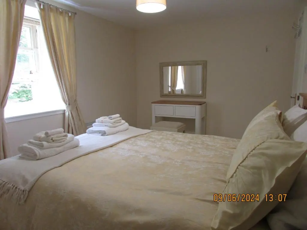 a bedroom with a large bed with towels on it at Culloden Stables 4 in Inverness