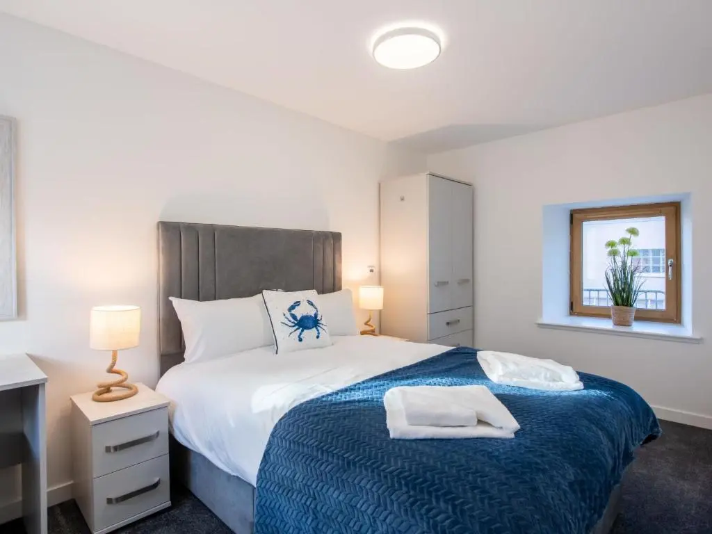 a bedroom with a bed with a blue blanket at Apartment Harbour Nights 4 by Interhome in Lossiemouth