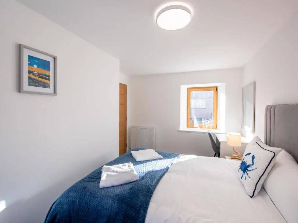a bedroom with a white bed with a blue blanket at Apartment Harbour Nights 4 by Interhome in Lossiemouth