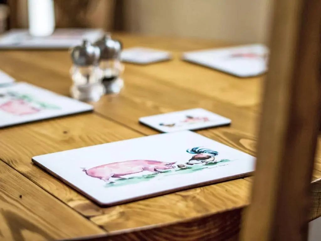 a wooden table with three plates with a pig on it at Holiday Home The Barn by Interhome in Drumnadrochit