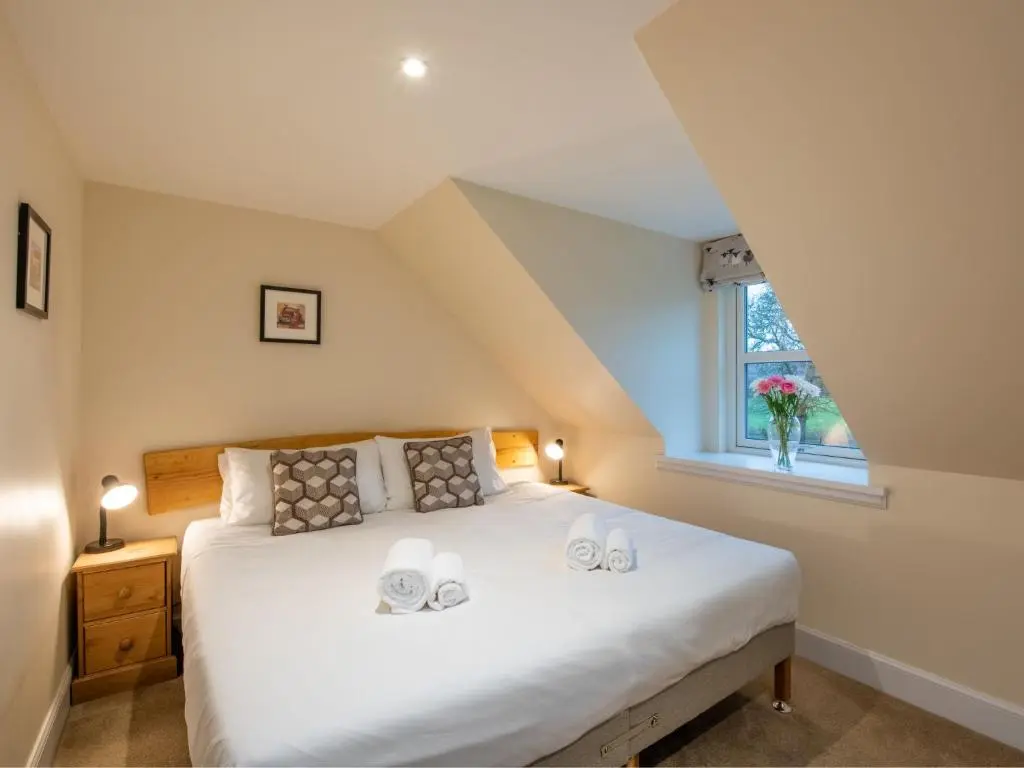 a bedroom with a large bed with two towels on it at Holiday Home The Barn by Interhome in Drumnadrochit