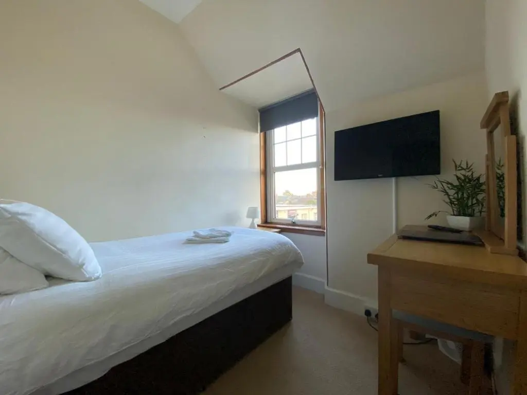 a bedroom with a bed and a desk and a television at Inverness Holiday House in Dalneigh