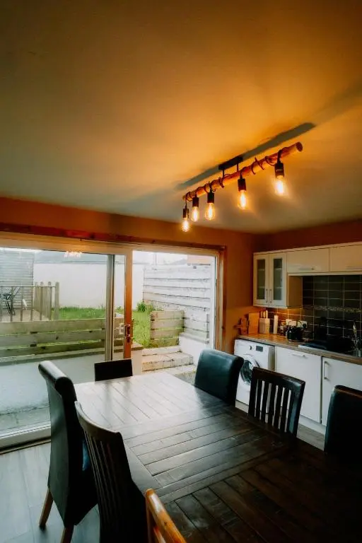 a dining room with a table and chairs and a kitchen at Inverness Holiday House in Dalneigh