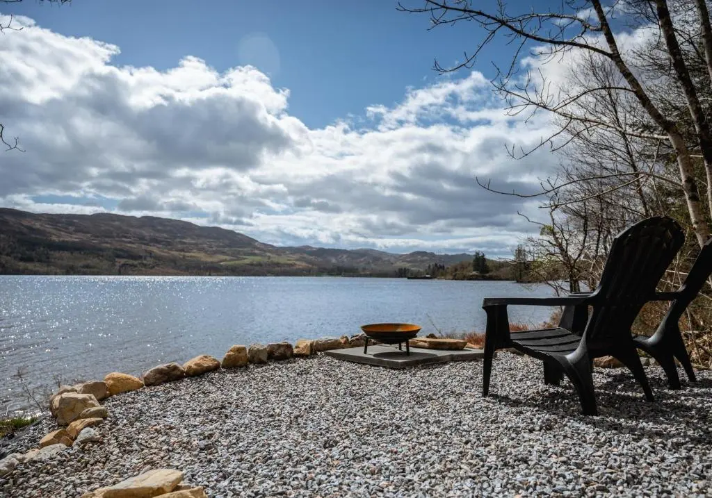 a chair and a table next to a lake at Alba Pod in Fort Augustus