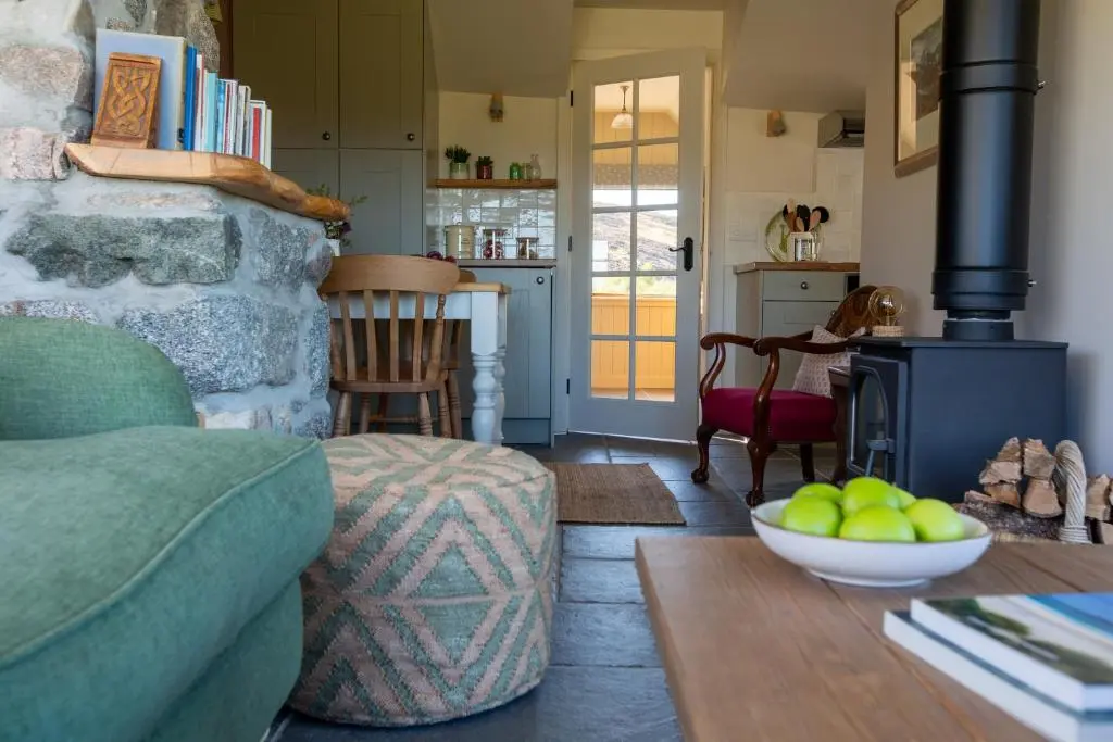 a living room with a green couch and a fireplace at The Stable Bothy in Rogart
