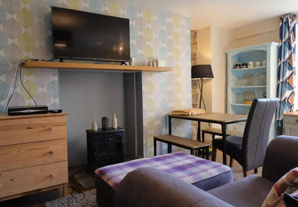 a living room with a couch and a table with a television at Fisherman's Rest in Helmsdale