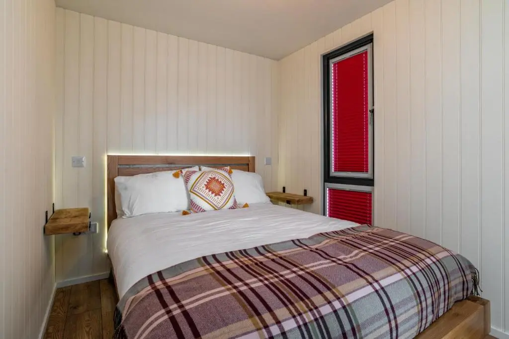 a bedroom with a bed and a red window at The Off Grid Cabin in Insch