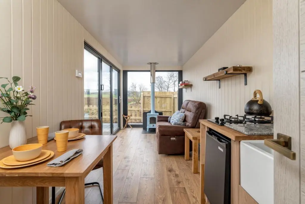 a kitchen and living room with a table and a stove at The Off Grid Cabin in Insch
