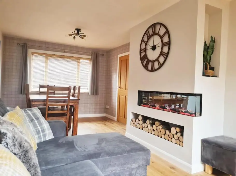 a living room with a fireplace with a clock on the wall at York Street Retreat, modern cosy 2 bed with garden in Dufftown