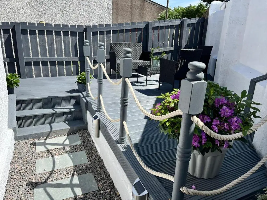 a deck with a rope and some chairs and flowers at 39 Wells Street Apartment in Inverness