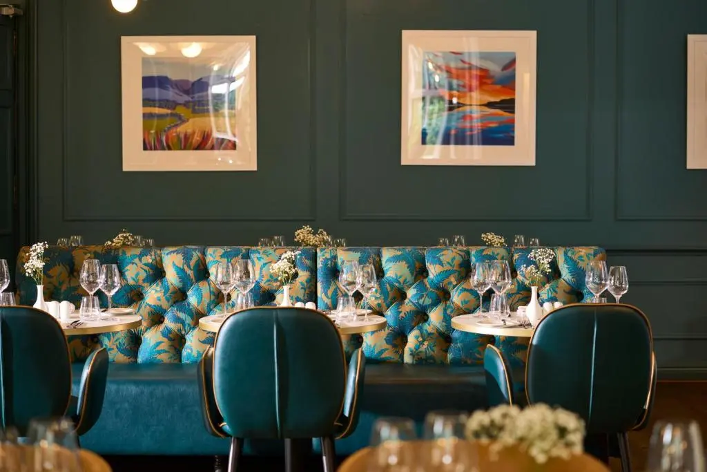a dining room with tables and a blue couch at Royal Marine Hotel, by Highland Coast Hotels in Brora