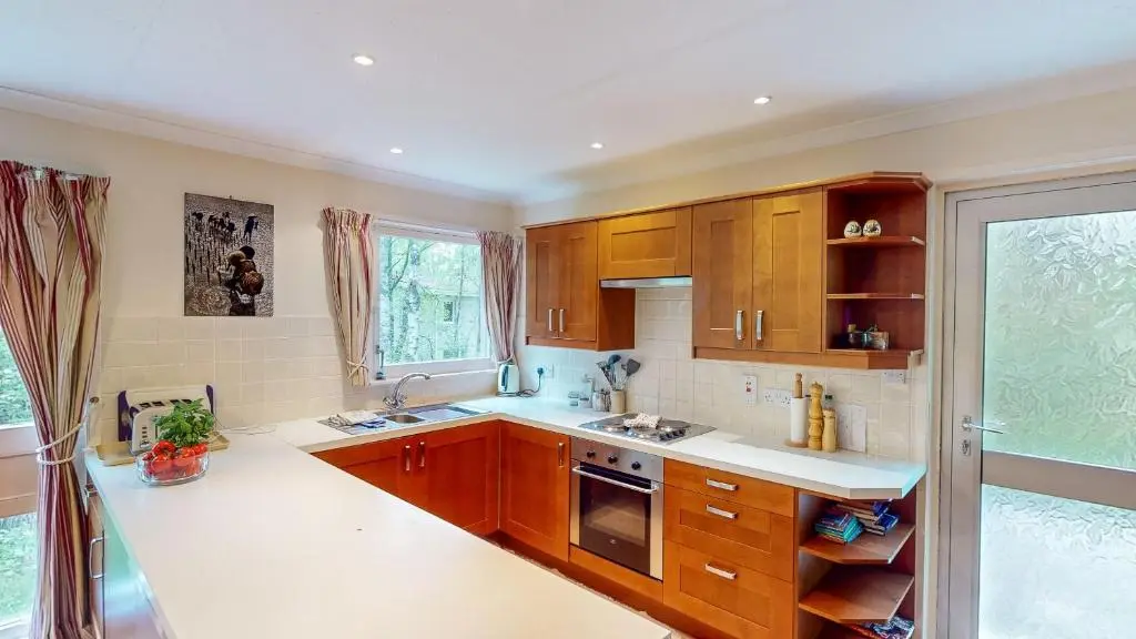 a kitchen with wooden cabinets and a large window at Torr Beatha in Kincraig