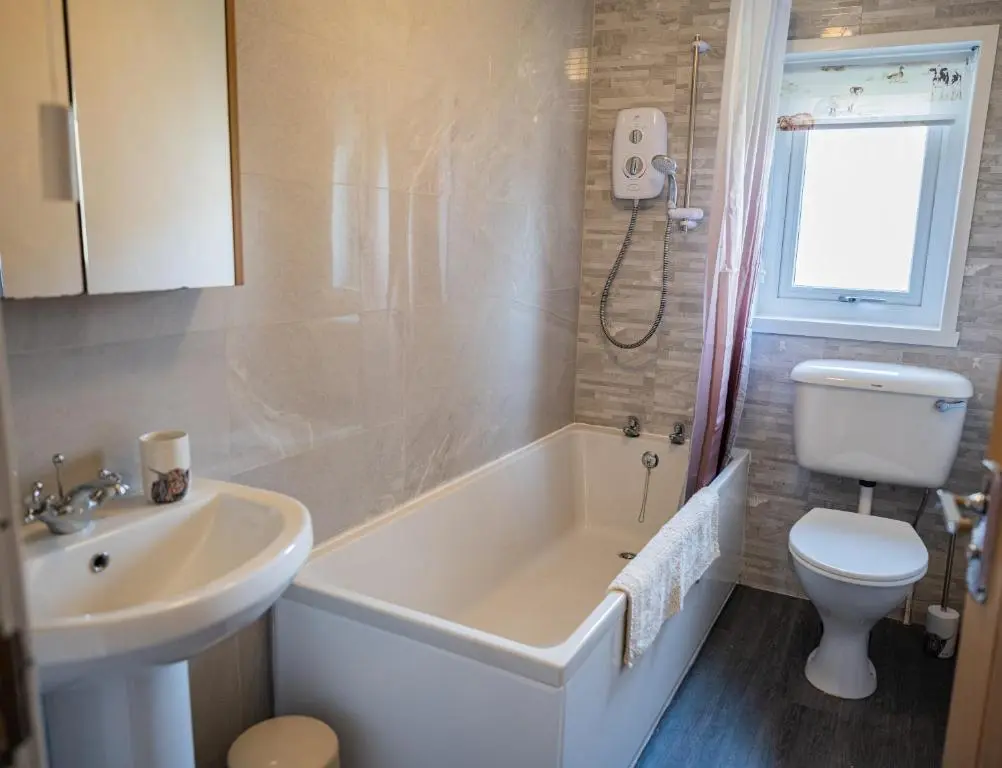 a bathroom with a tub and a toilet and a sink at North Coast Cottage - Coastal Highland Retreat with Sea Views in Portgower