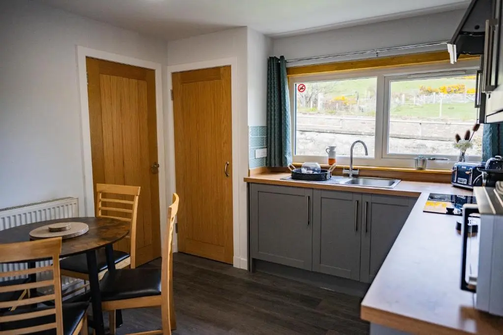 a kitchen with a table and a sink and a window at North Coast Cottage - Coastal Highland Retreat with Sea Views in Portgower
