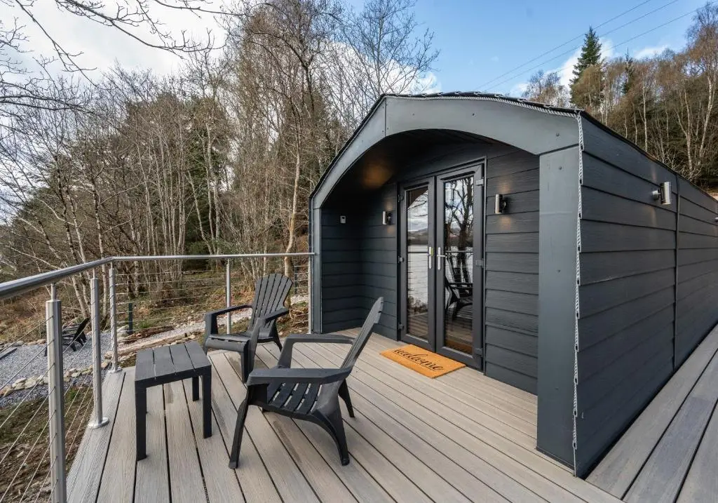 a black shed with two chairs and a table on a deck at Nessie Pod in Fort Augustus