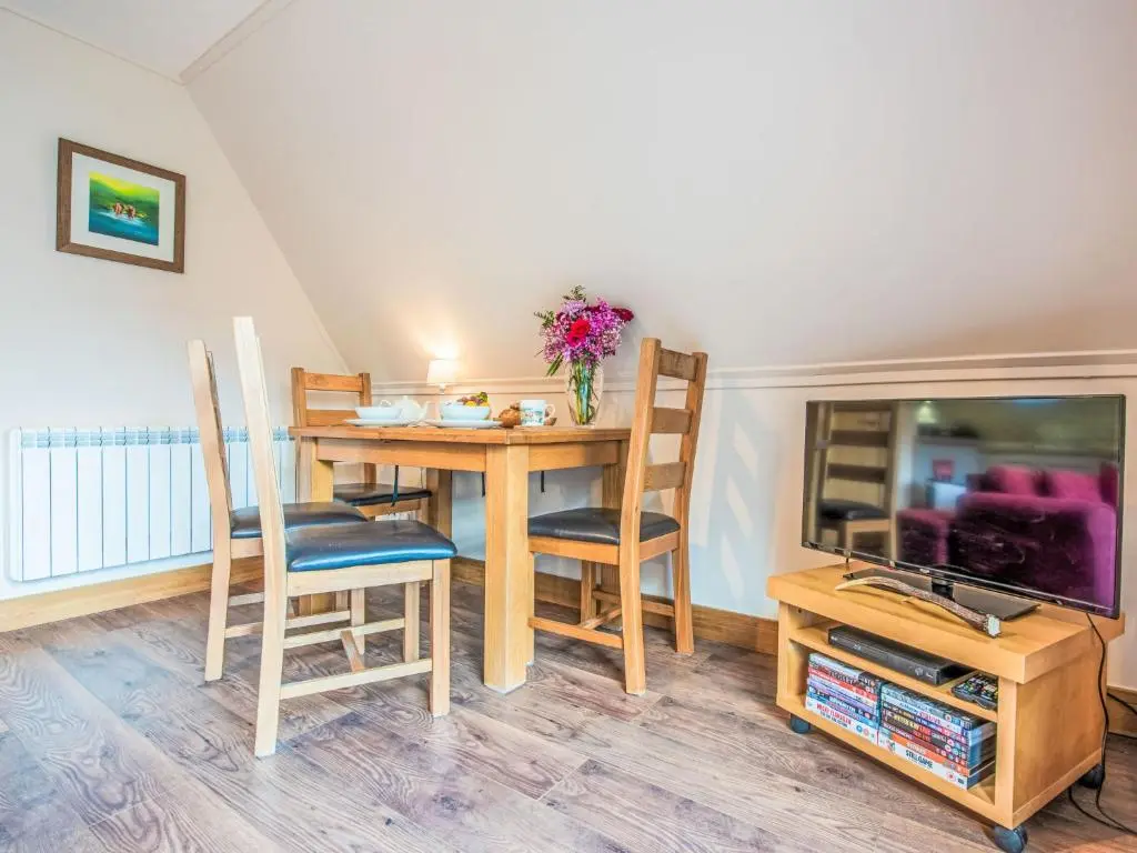 a dining room with a table and chairs and a tv at Chalet Loch Lochy Retreat by Interhome in Spean Bridge