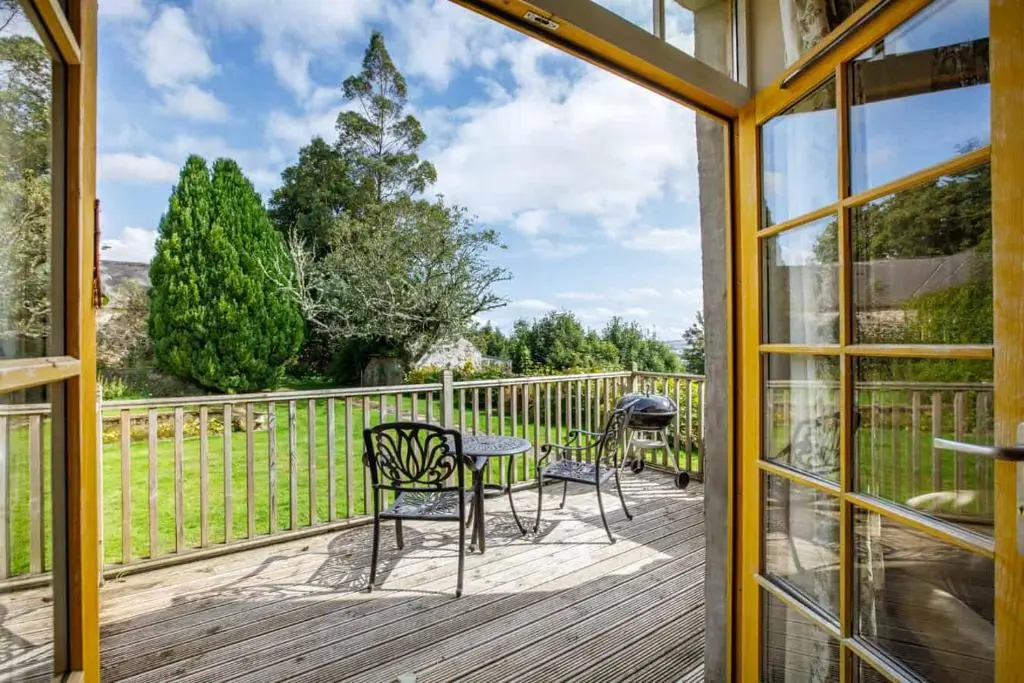 a screened in porch with chairs and a table at Little Fyrish in Evanton