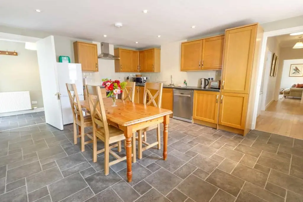 a kitchen with a wooden table with chairs and a refrigerator at Little Fyrish in Evanton