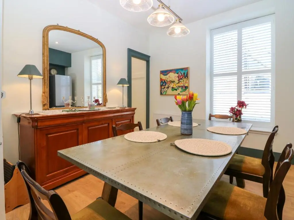 a dining room with a table and a mirror at 1A Carmelite Street in Banff